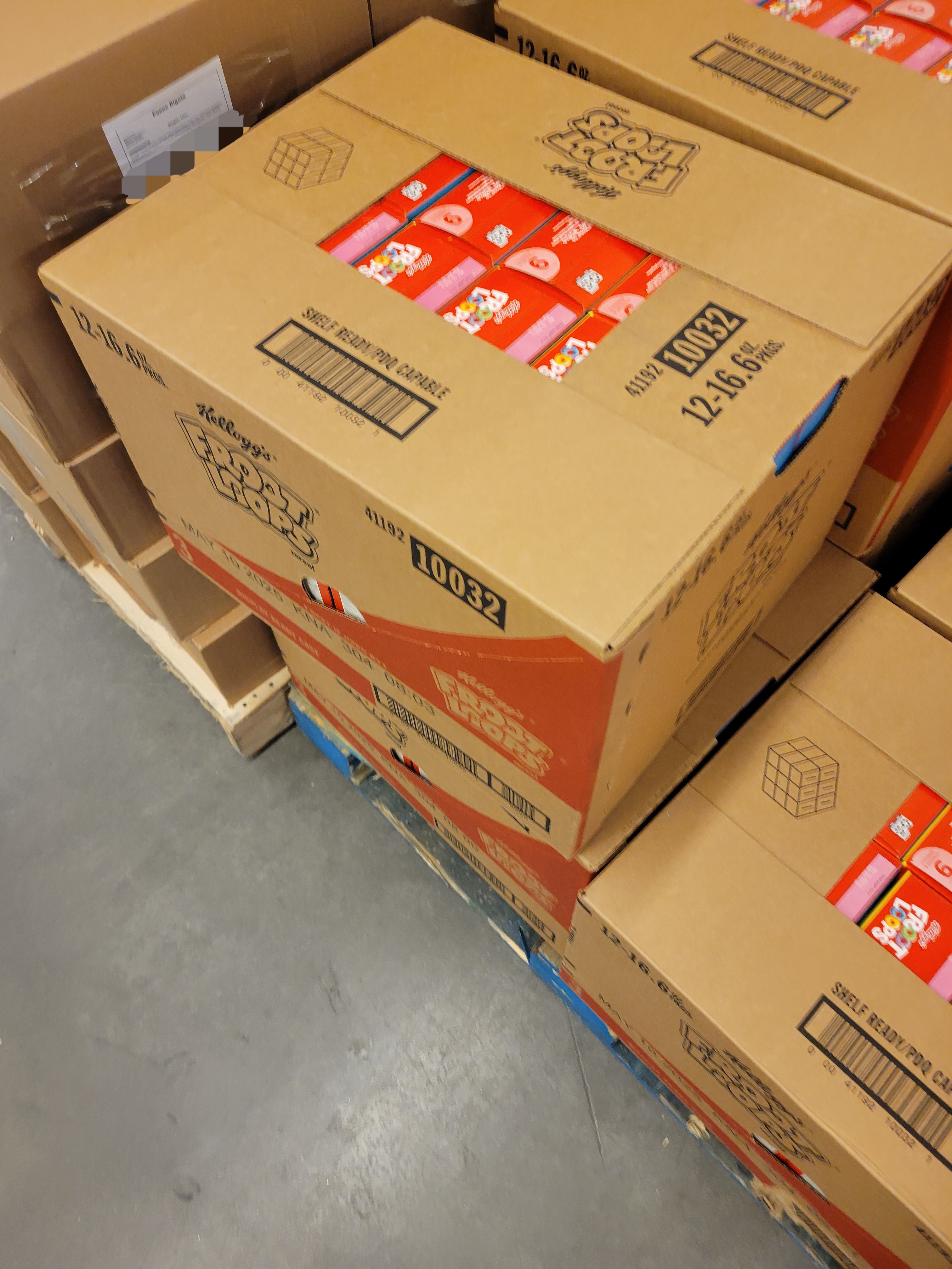 Cardboard boxes filled with boxes of fruit loops cereals on a wooden pallet.